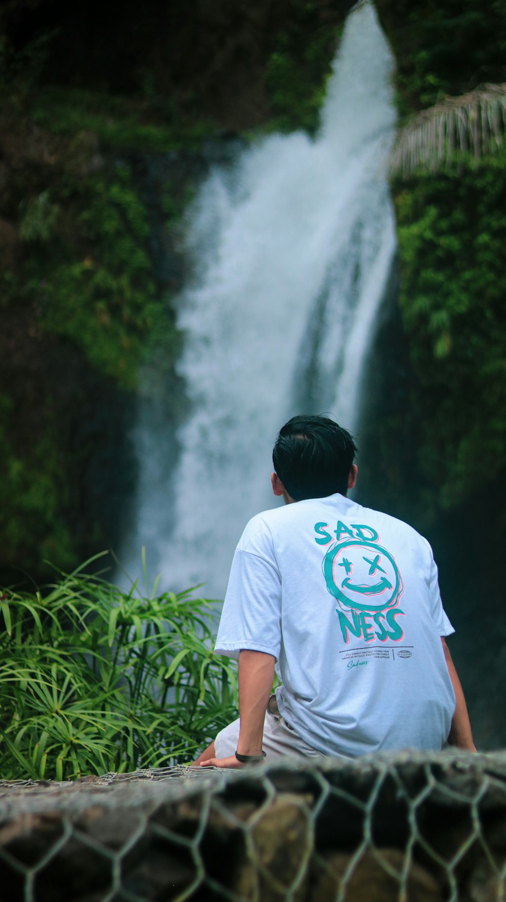 a man sitting in front of a waterfall