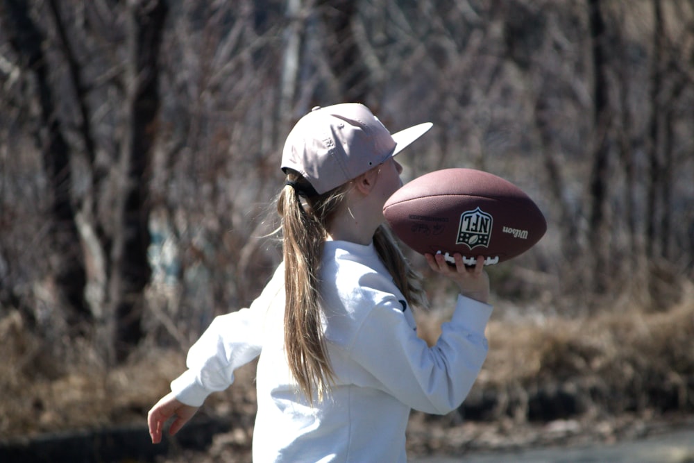 a young girl holding a football in her right hand