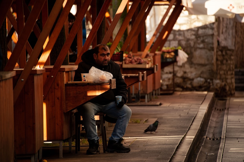 a man sitting on a bench next to a bird
