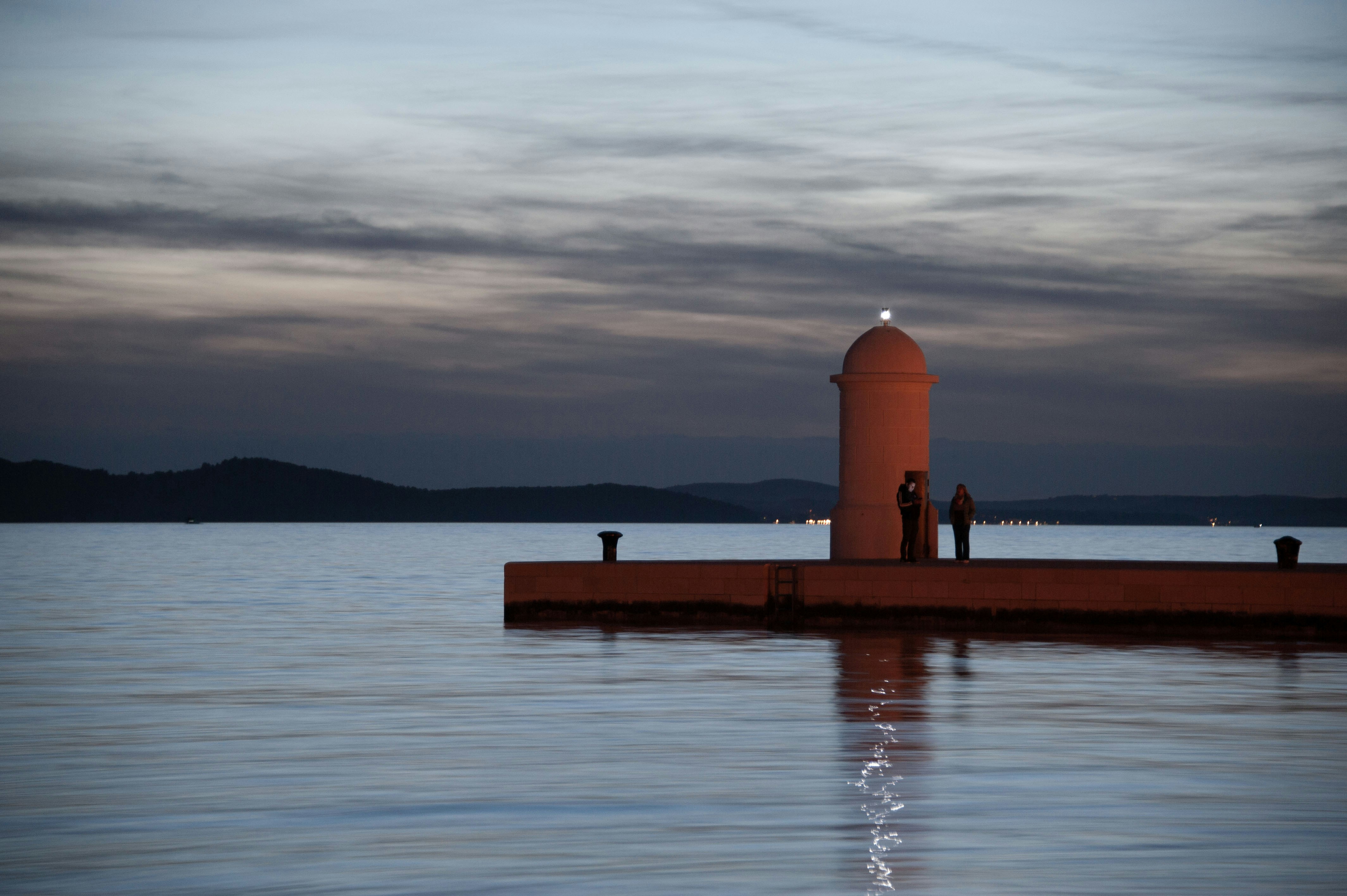 a lighthouse sitting on top of a pier next to a body of water, 