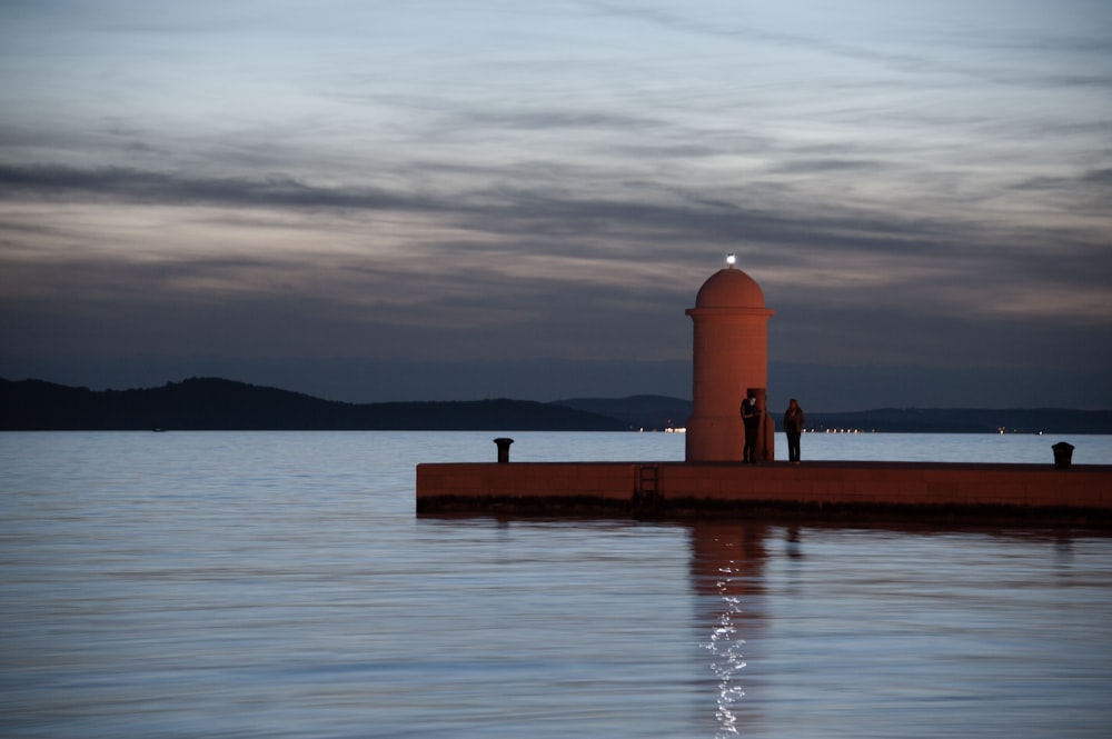 Un faro sentado en la parte superior de un muelle junto a un cuerpo de agua