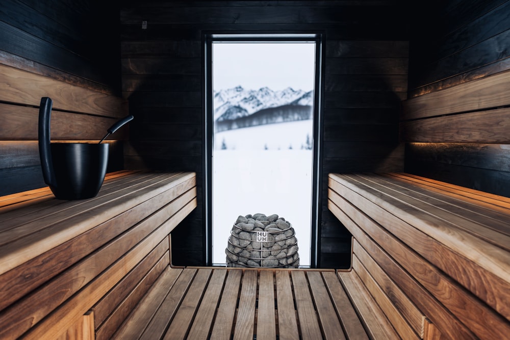 eine Holzsauna mit Fenster und einem Stapel Steine