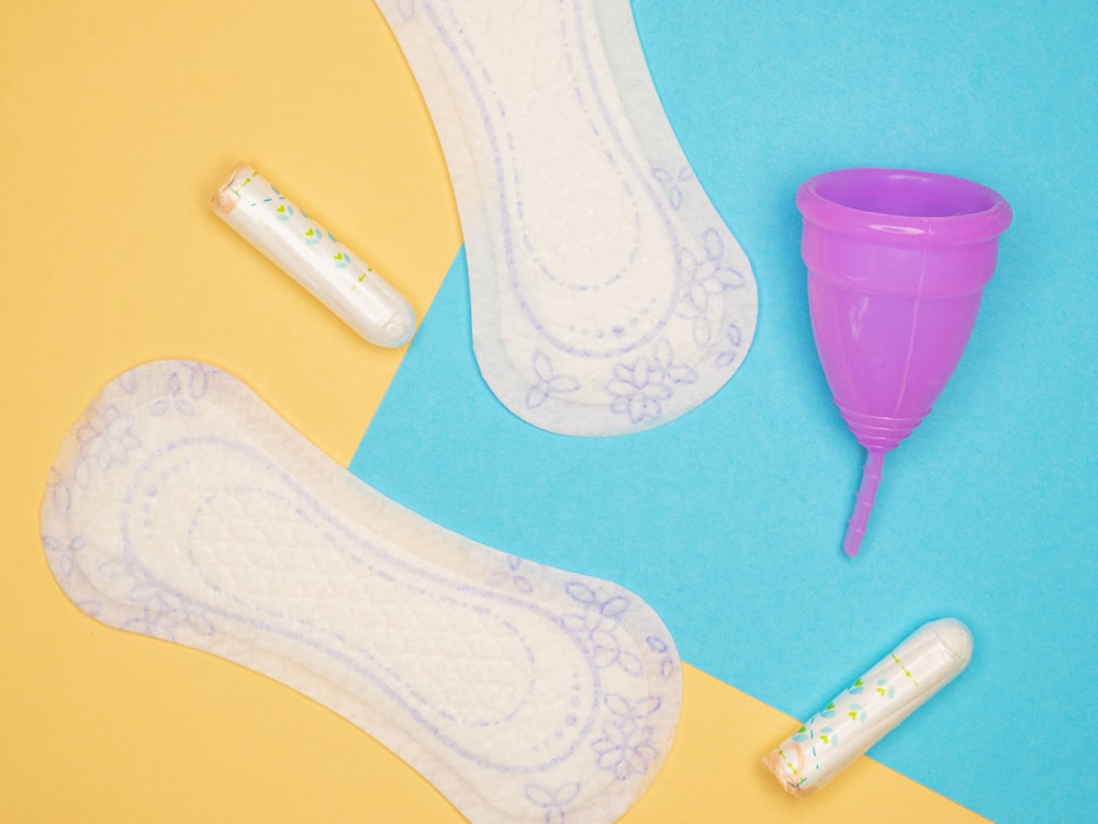 a pair of white socks and a purple cup on a blue and yellow background