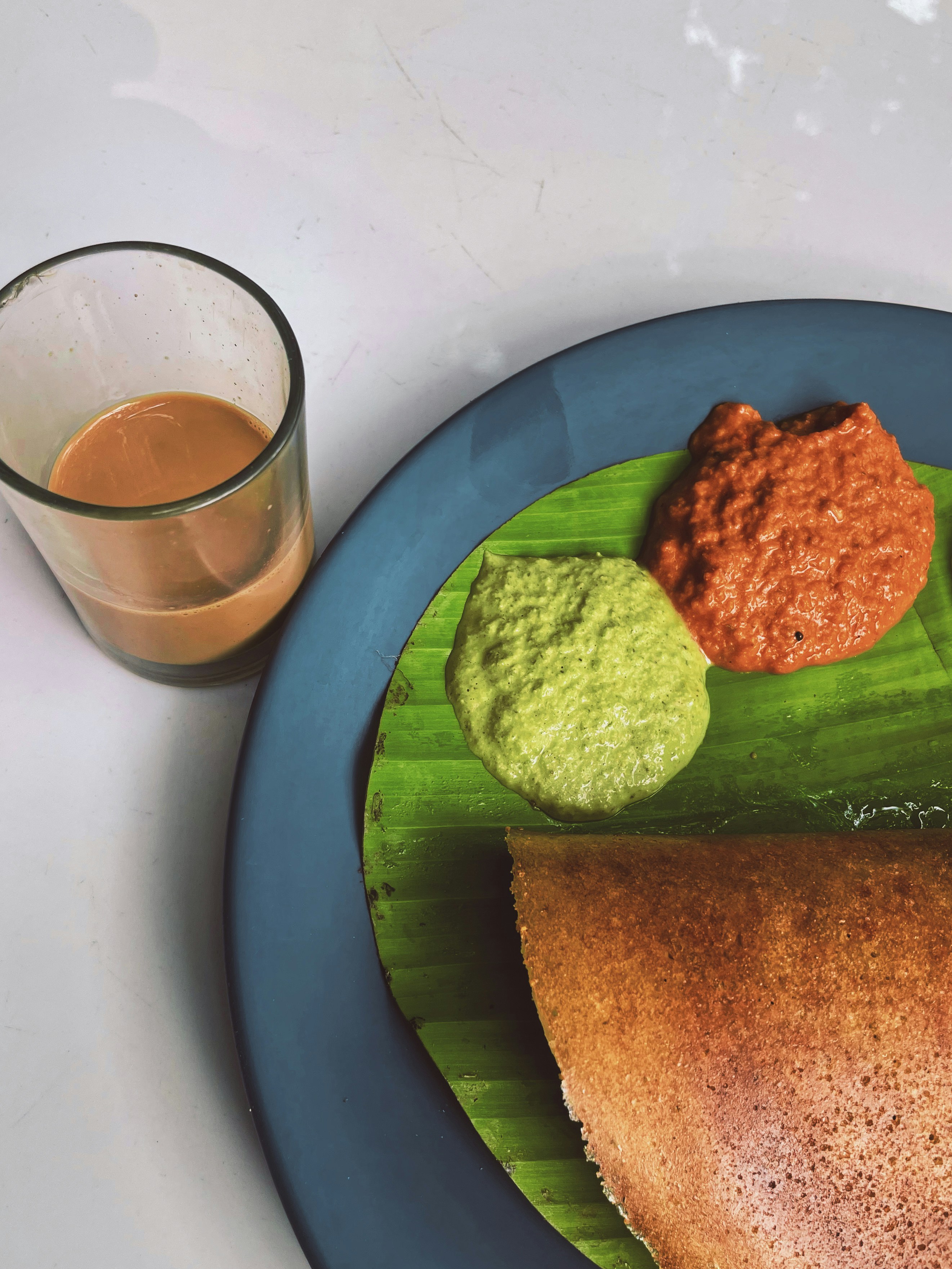 Thin crisp dosa on a banana leaf with chutneys
