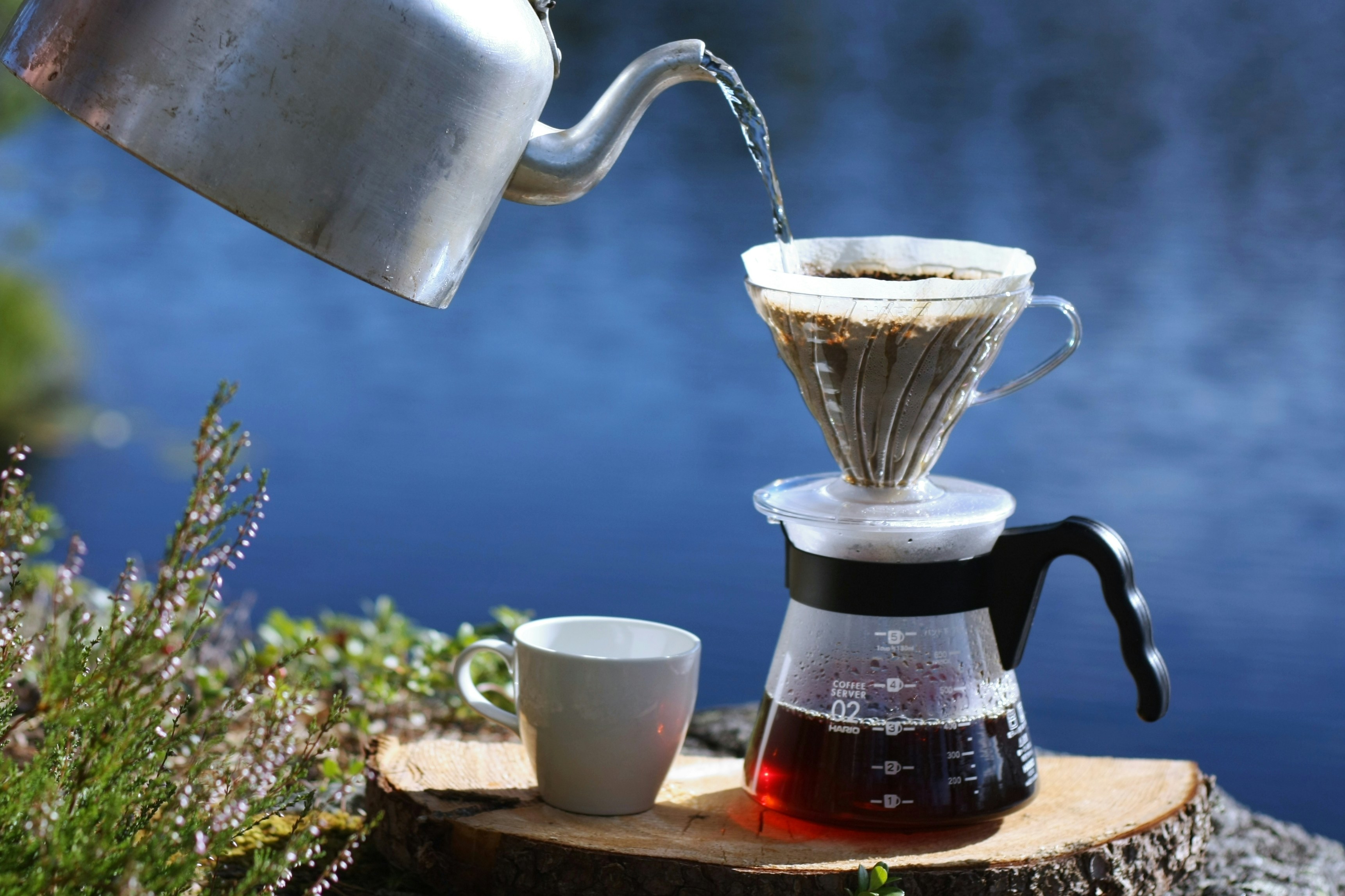 uma cafeteira despejando água em uma xícara