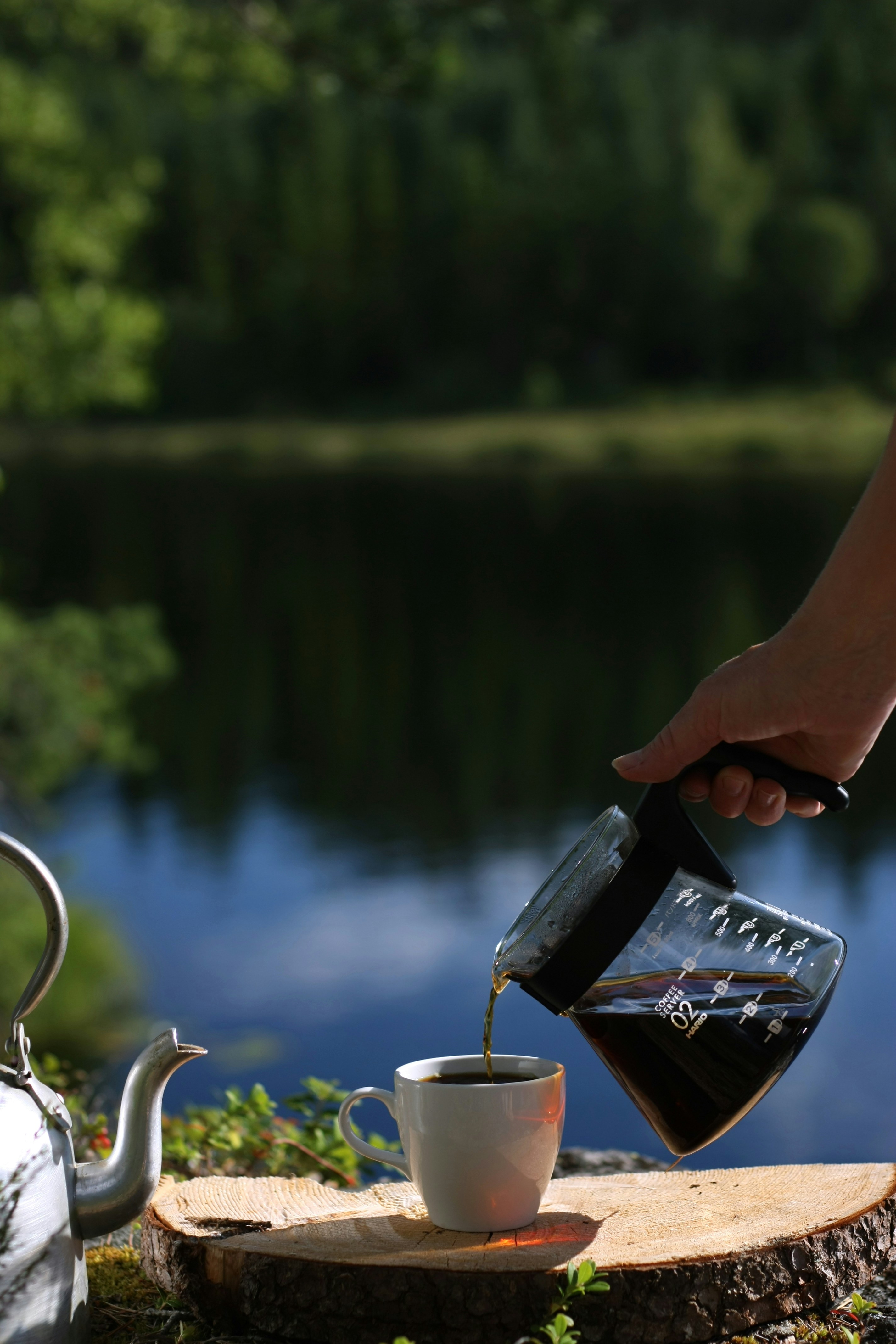 a person pouring a cup of coffee into a teapot