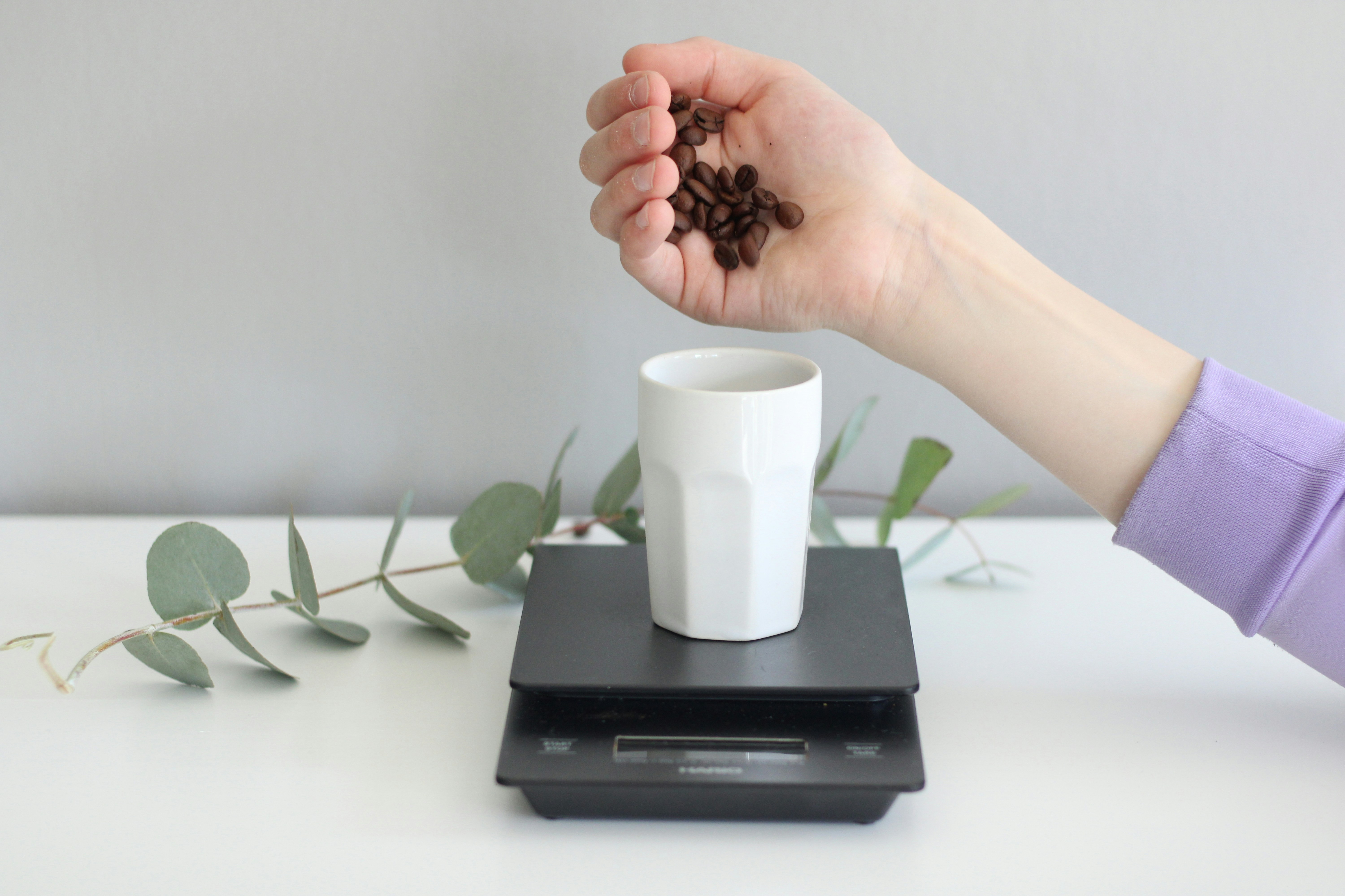 a person holding a handful of coffee beans over a scale