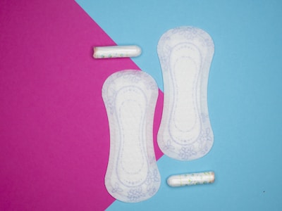 a pair of sanitary pads next to two pills