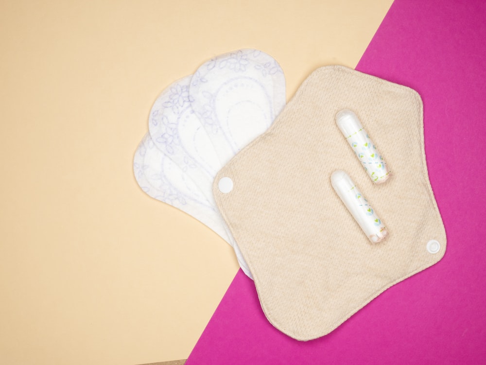 a pair of diapers and a cloth pad on a pink and yellow background