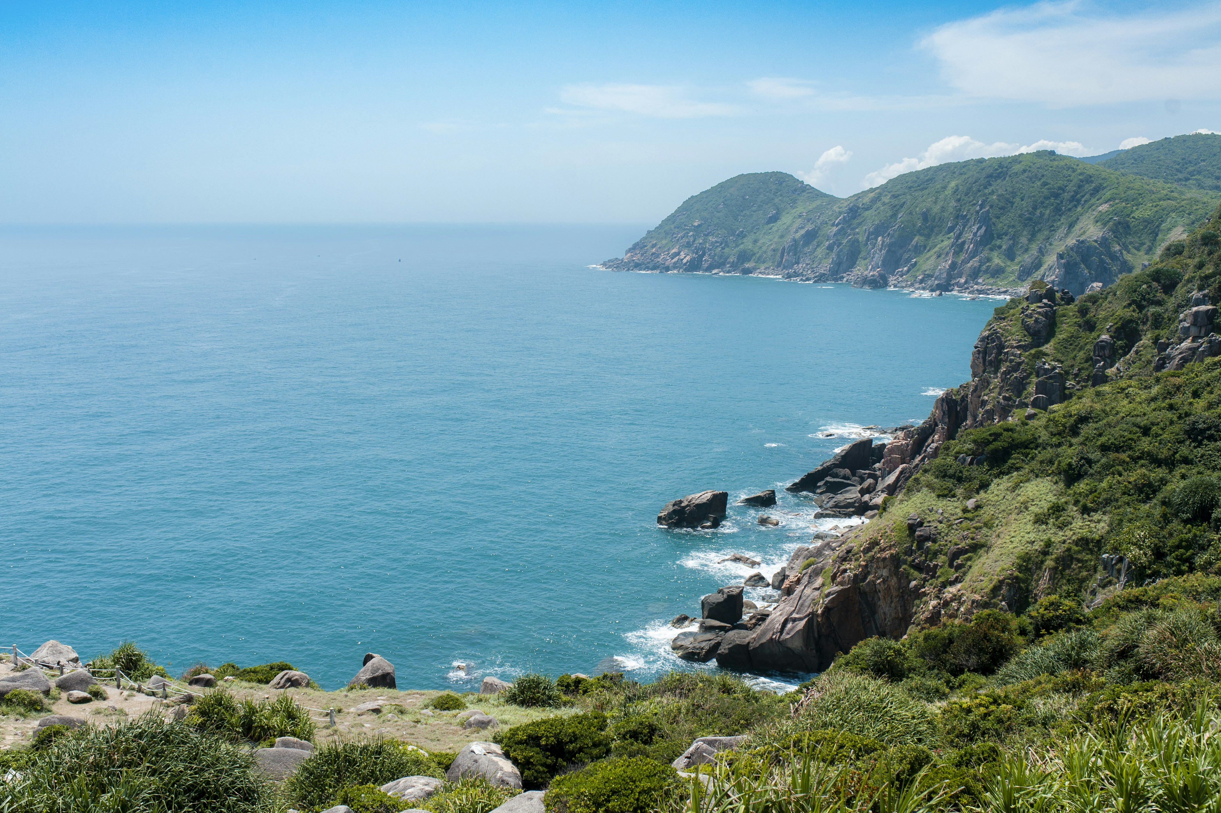 a large body of water sitting next to a lush green hillside