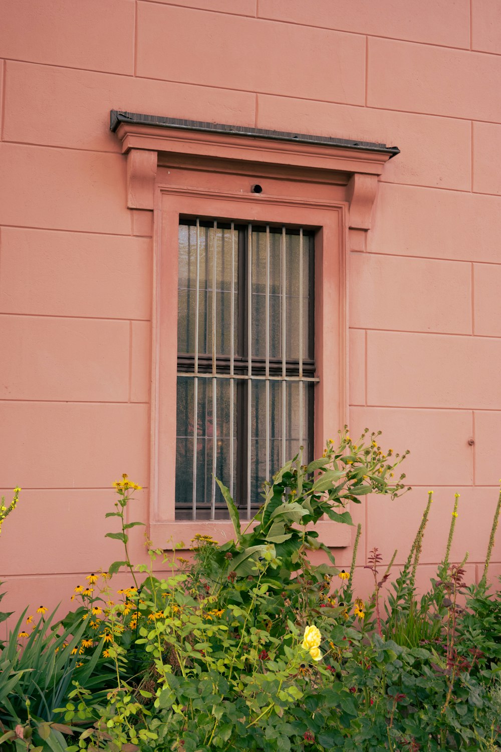 a window with bars on the side of a pink building