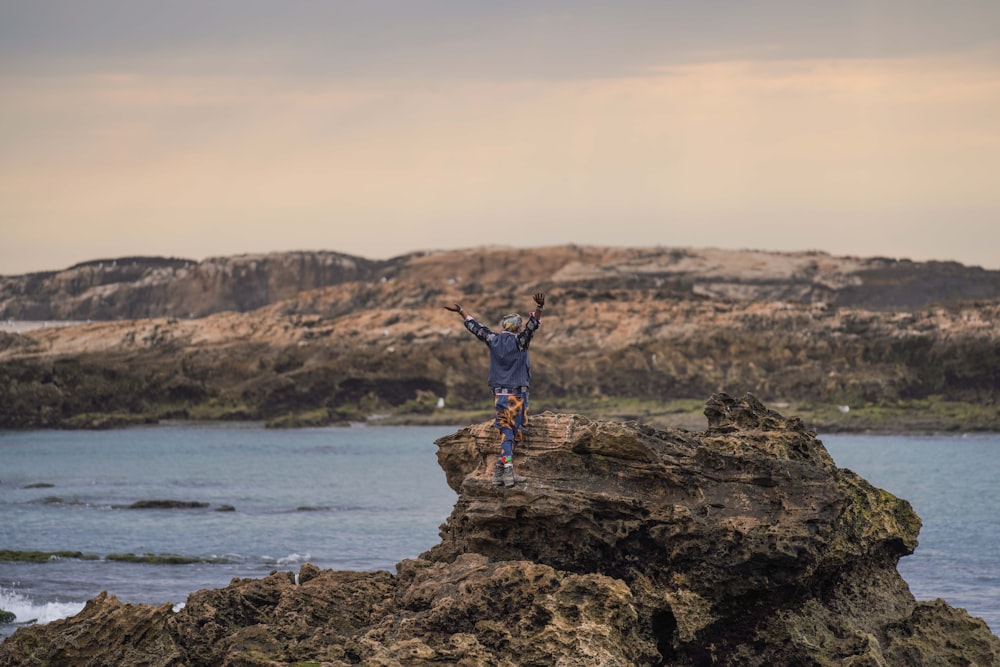 a man standing on top of a rock near the ocean