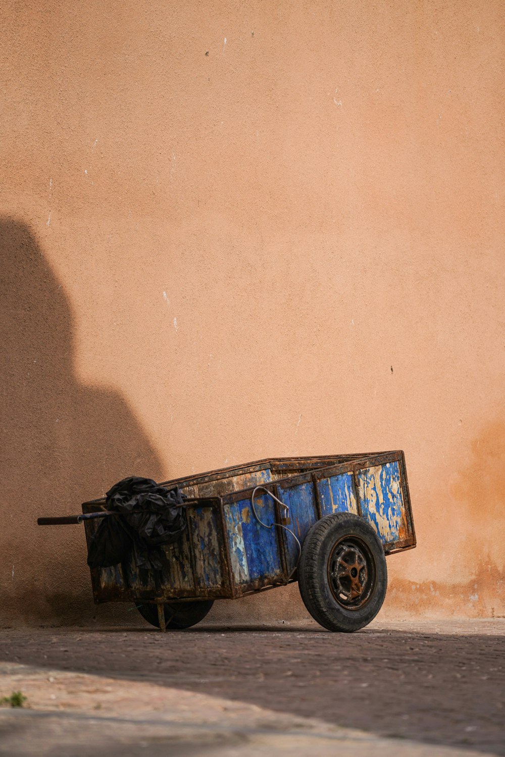 a rusty cart sitting on the side of a building