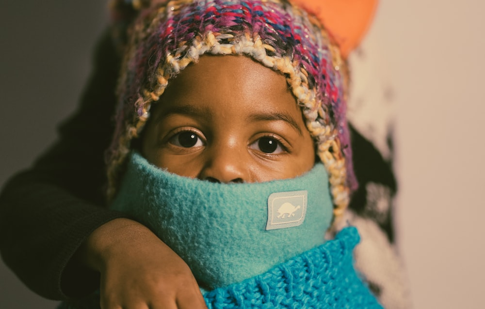 a young child wearing a knitted hat and scarf