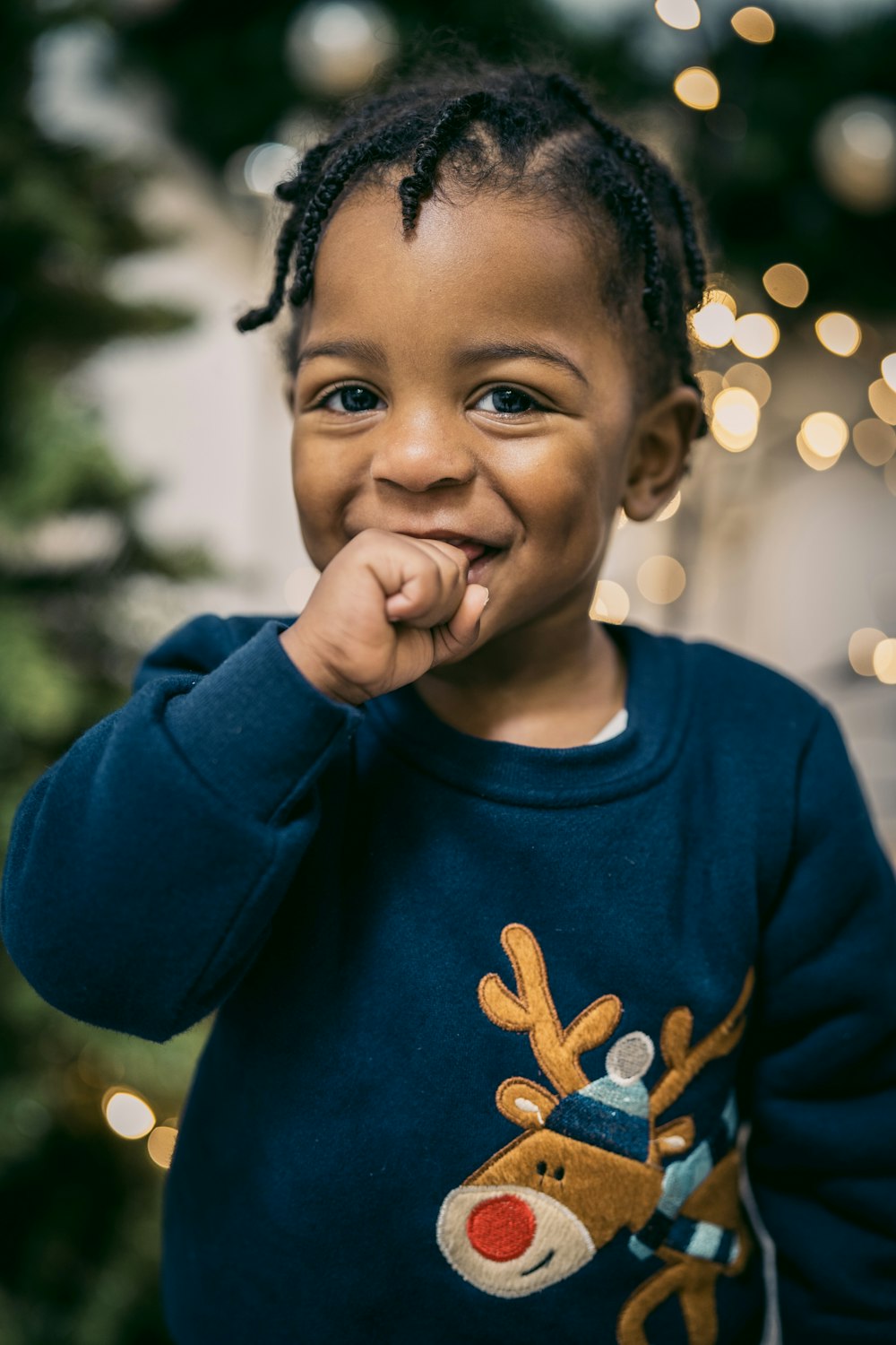 a young child standing in front of a christmas tree