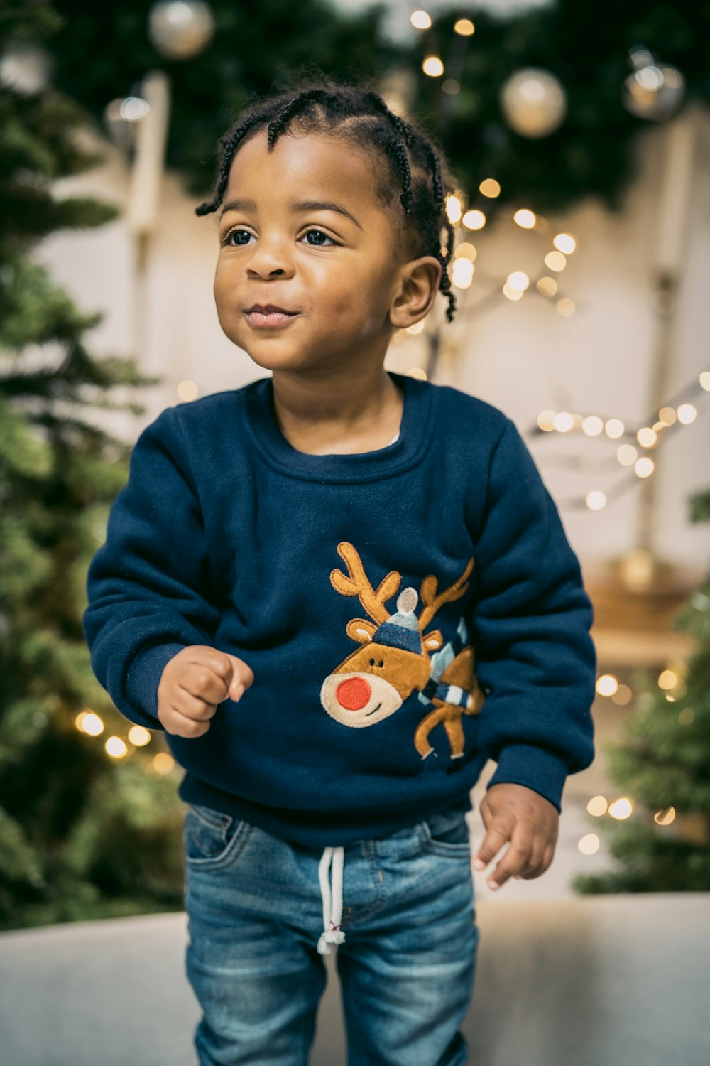 a young child standing in front of a christmas tree