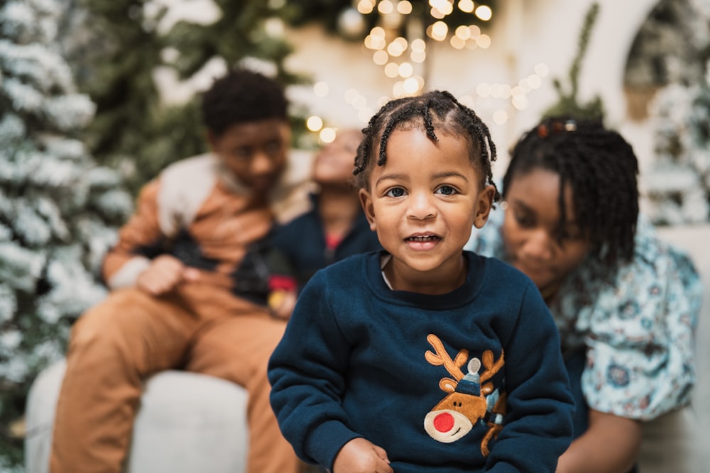 a little boy sitting on a couch with his family