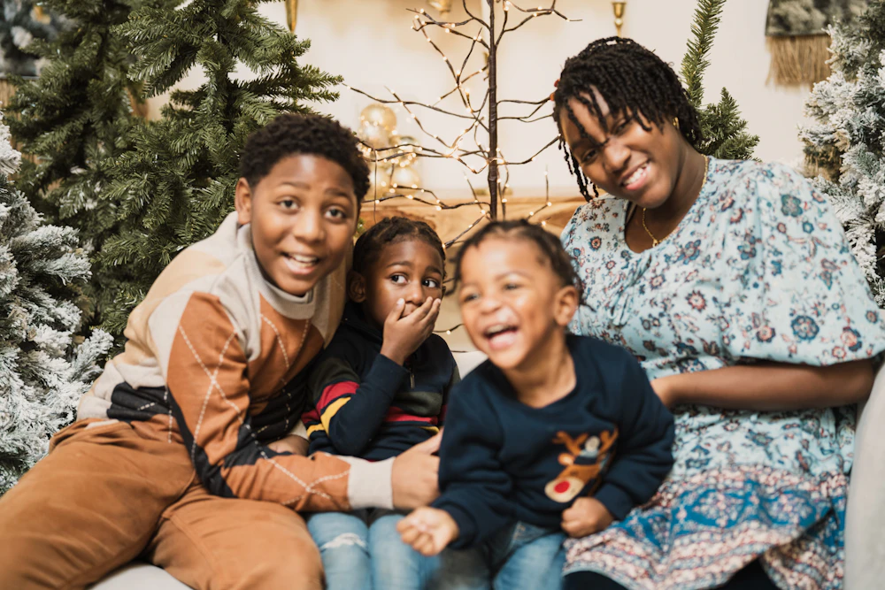 Mother and three children laughing together by a Christmas tree