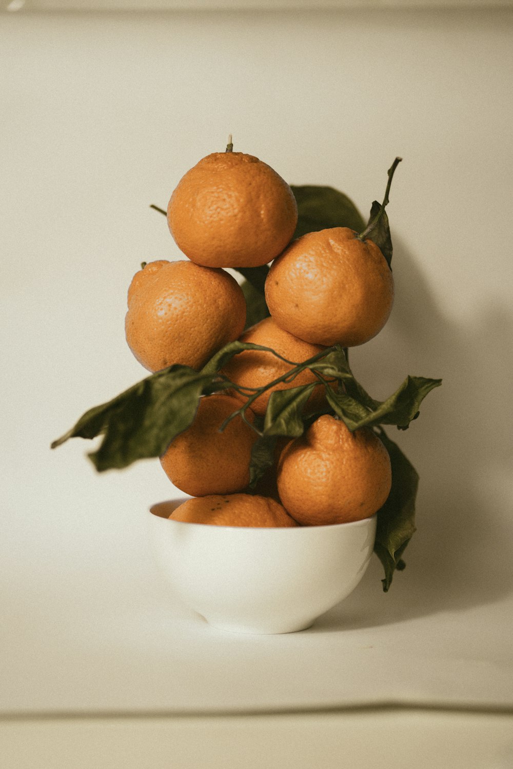 a white bowl filled with oranges on top of a table