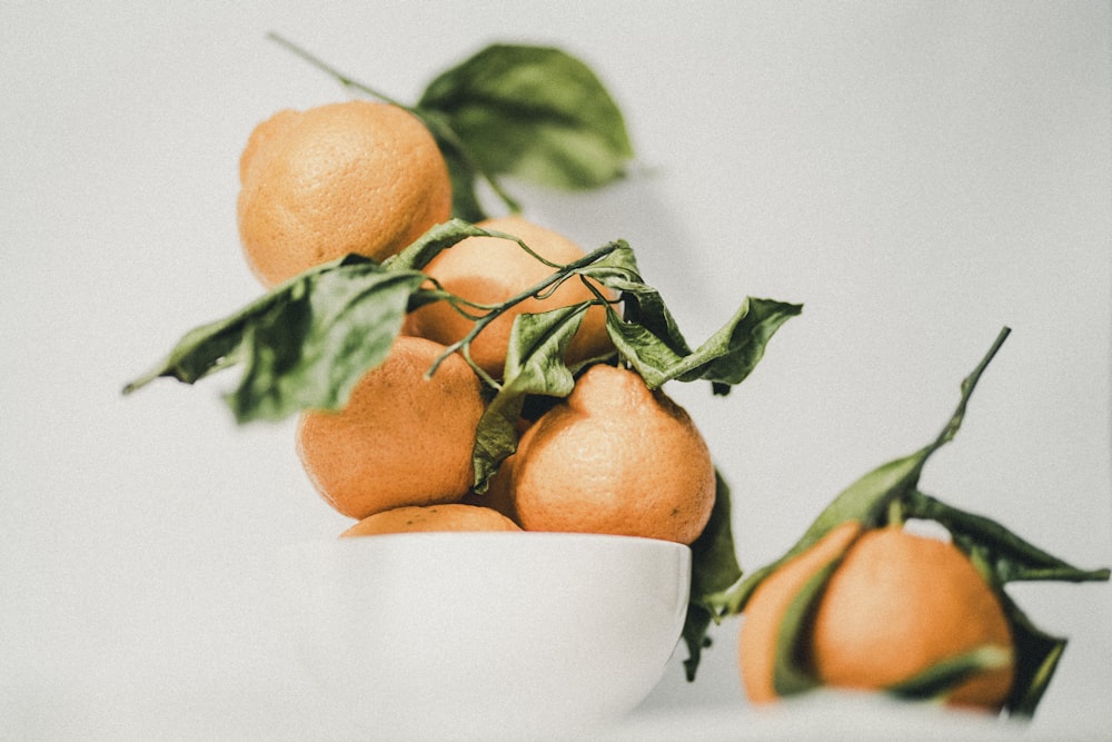 a white bowl filled with oranges on top of a table