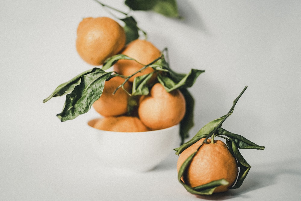 a white bowl filled with oranges on top of a table