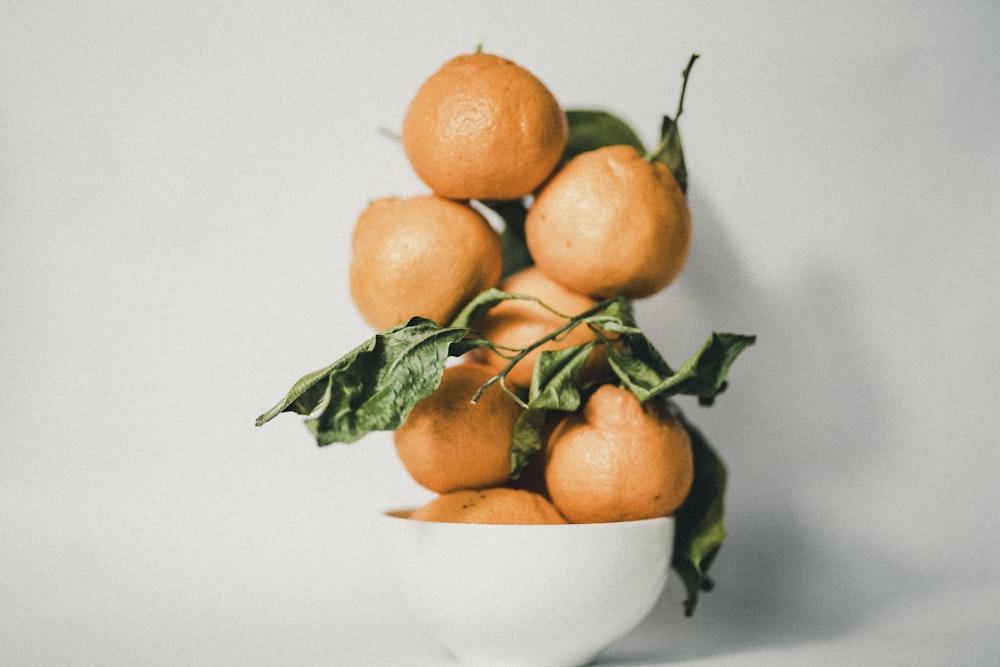 a white bowl filled with oranges on top of a table