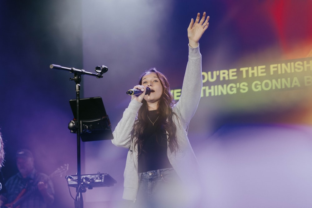 a woman singing into a microphone on stage