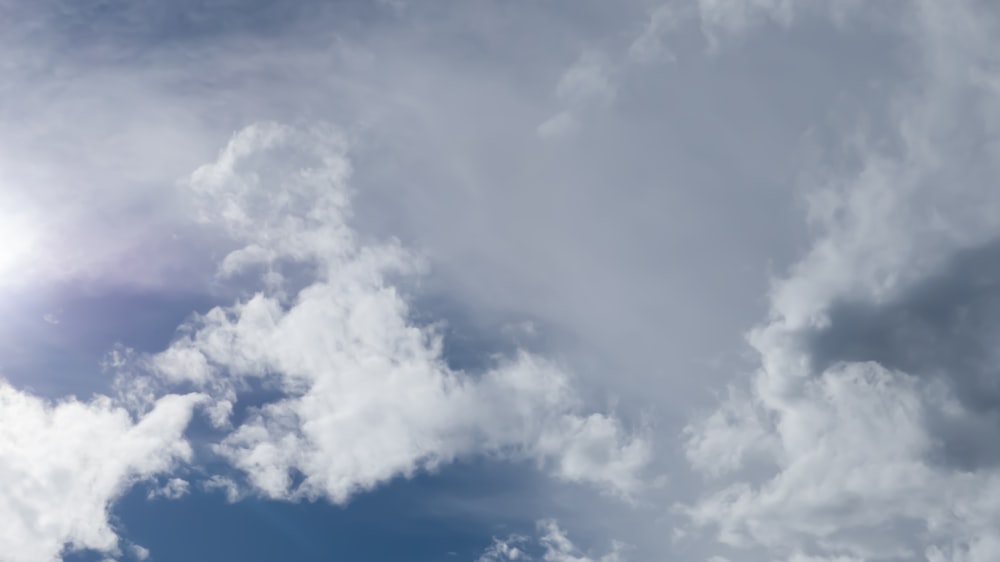 a plane flying through a cloudy blue sky