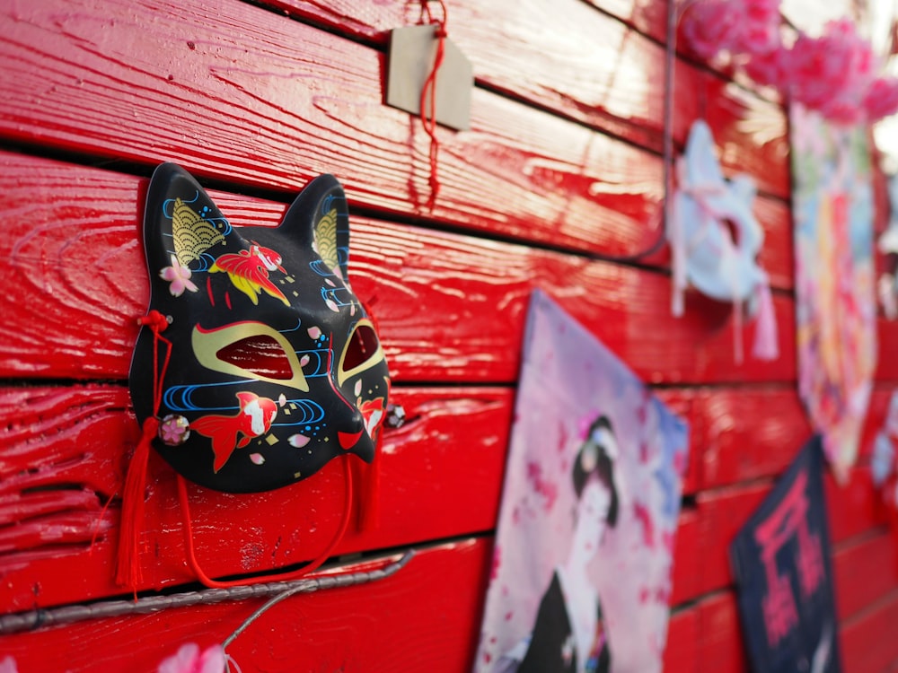 a cat mask is hanging on a red wall