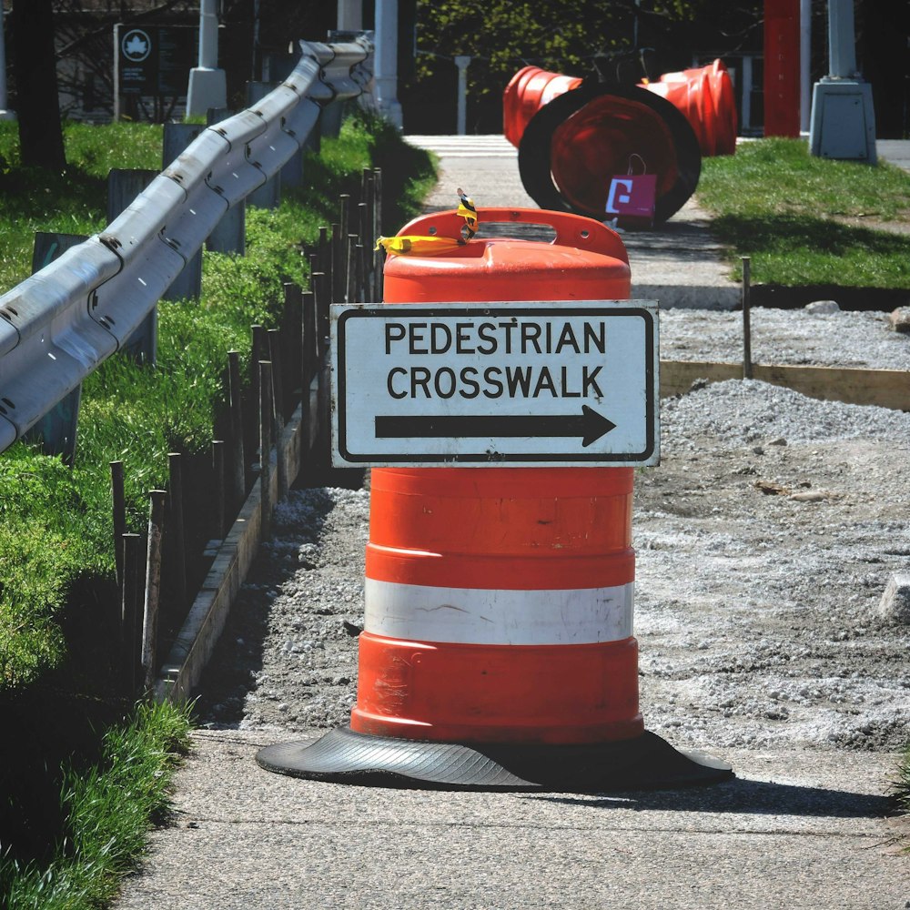 a red and white traffic cone sitting on the side of a road