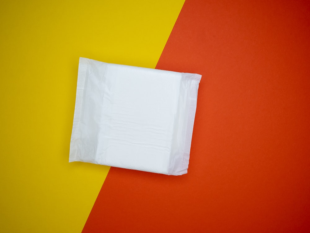 un pezzo di tessuto bianco seduto sopra uno sfondo rosso e giallo