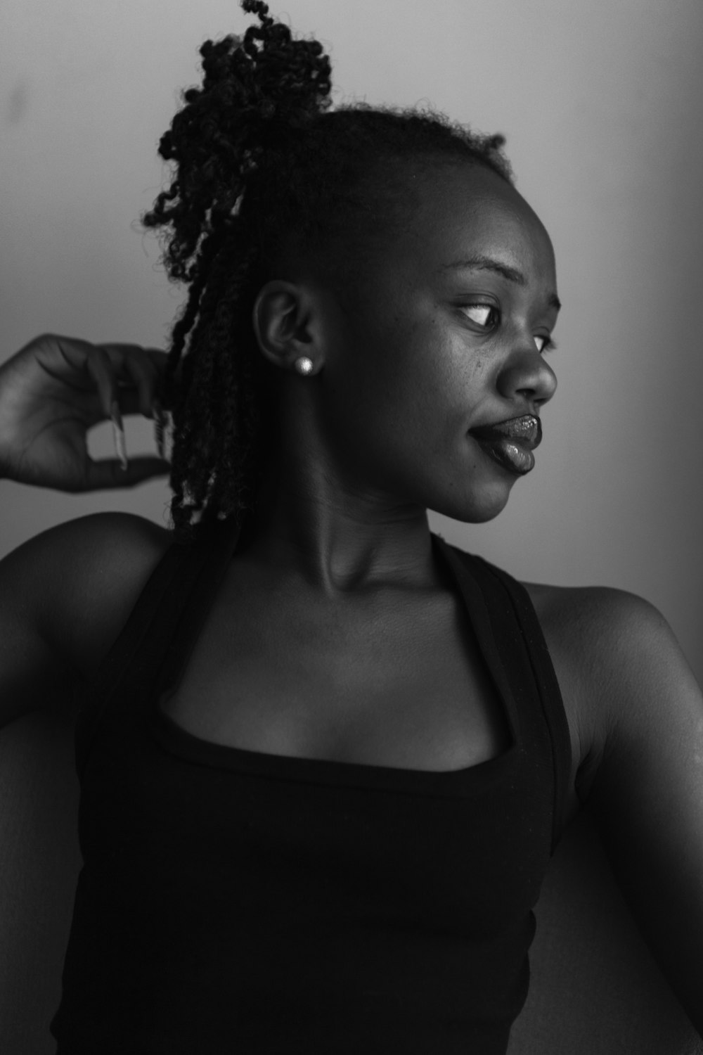 a woman in a black tank top is pulling her hair