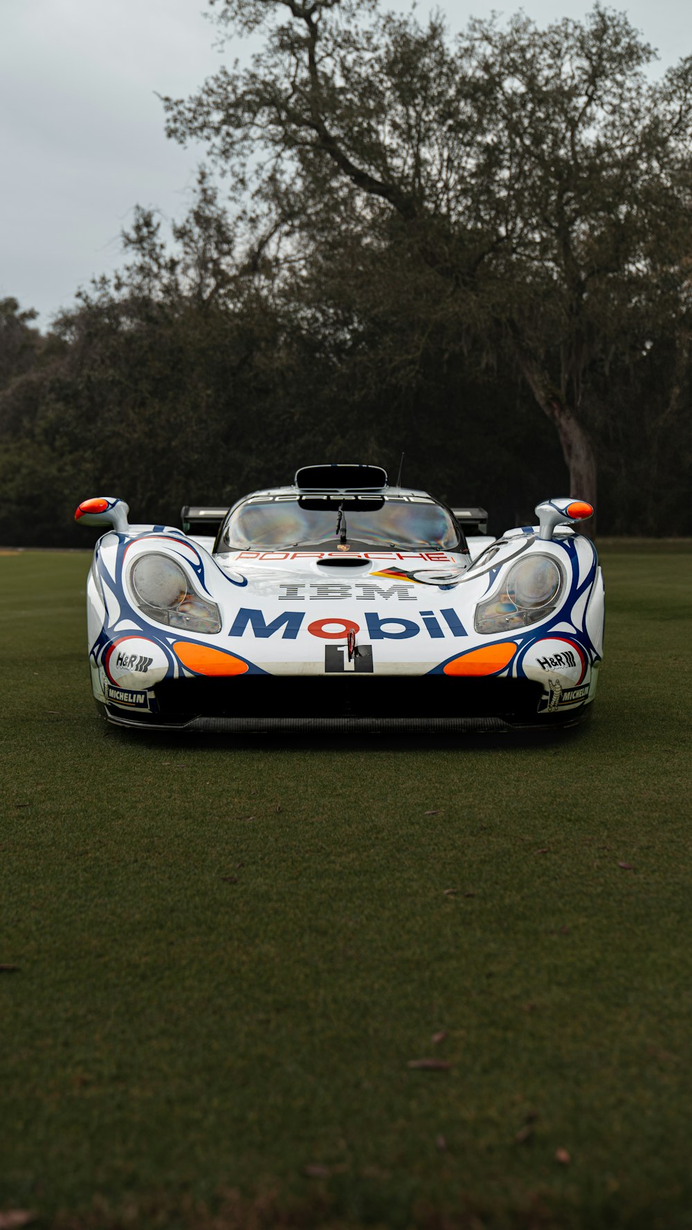 a white and orange race car sitting on top of a lush green field