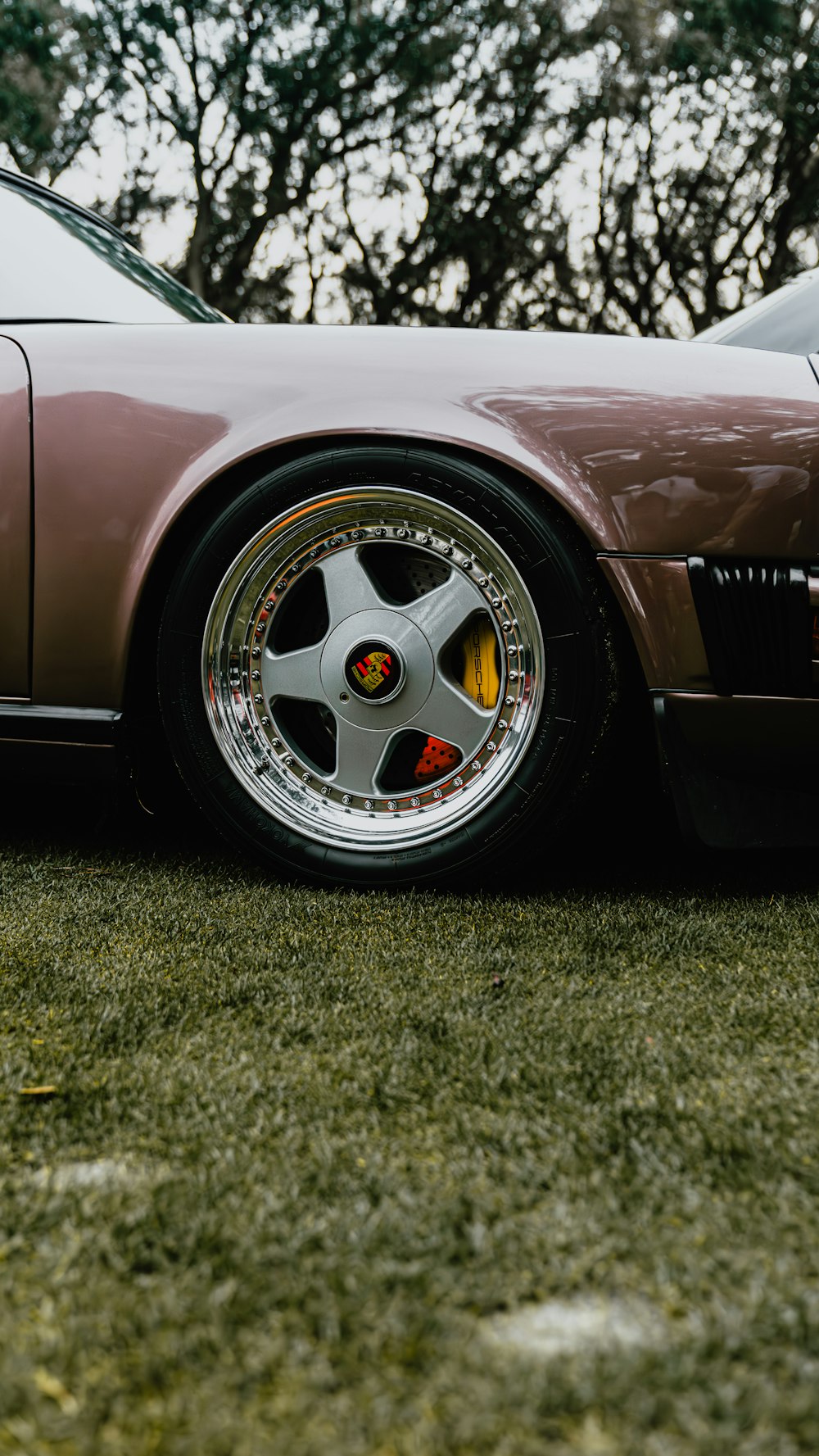 a brown sports car parked on top of a lush green field