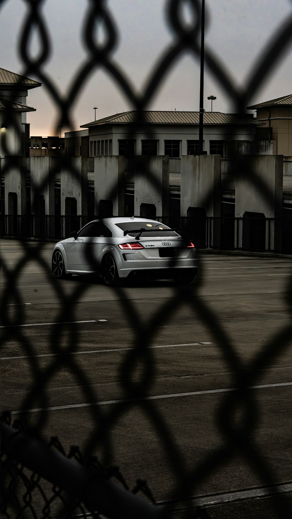 a car parked in a parking lot behind a chain link fence