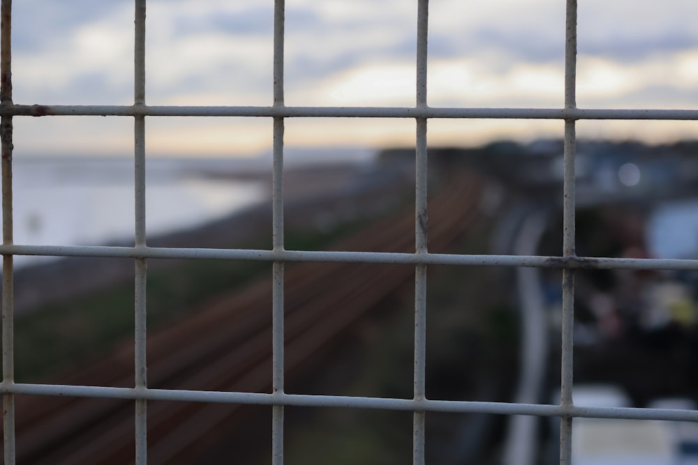 a close up of a fence with a train track in the background