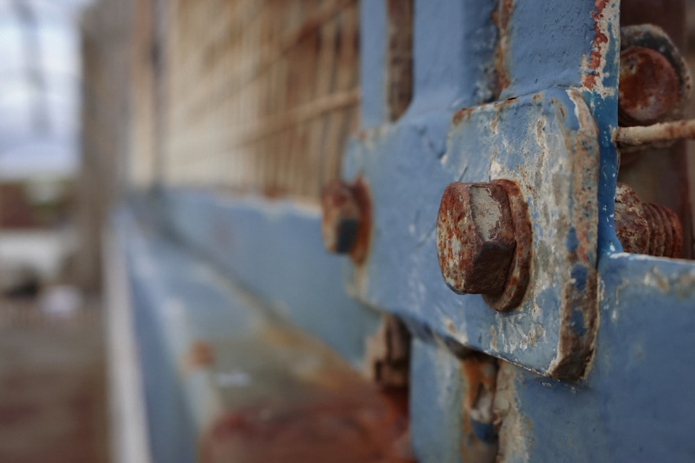 a close up of a blue door with rust on it