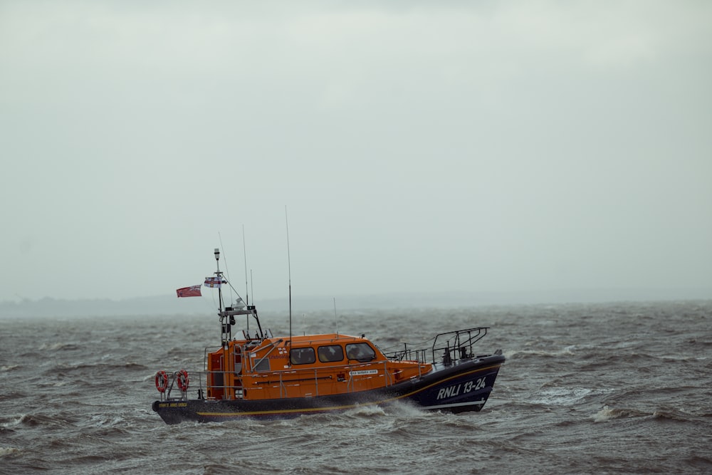 a small orange boat in the middle of the ocean