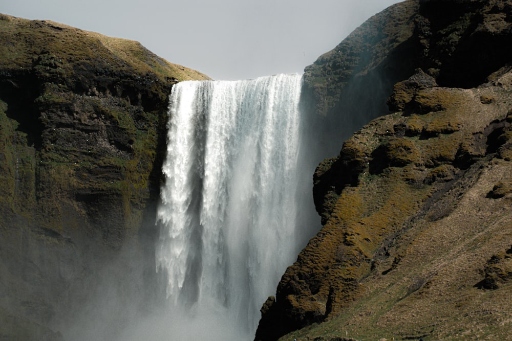 a large waterfall with a man standing in front of it