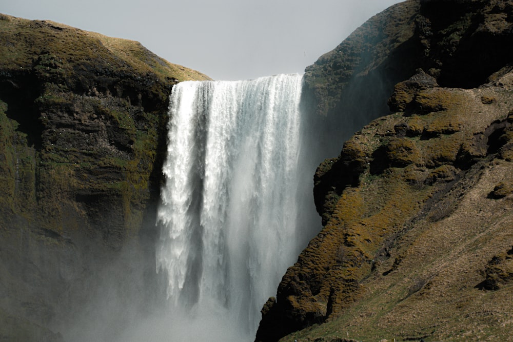 une grande cascade avec un homme debout devant elle