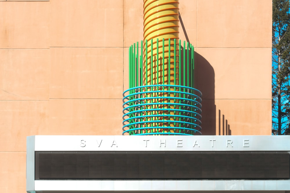 a yellow and green sculpture on the side of a building