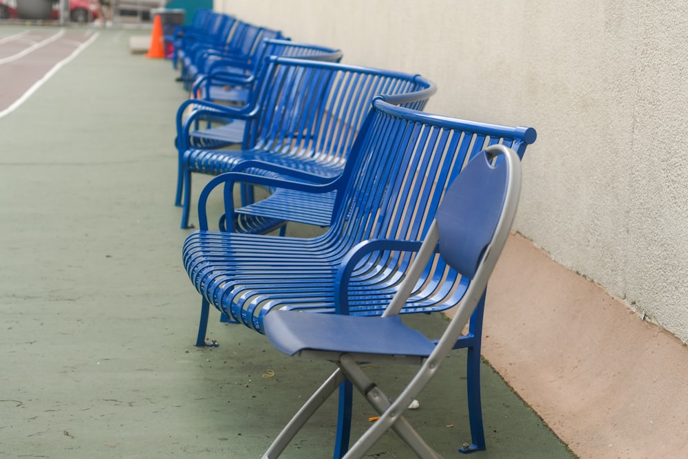a row of blue park benches sitting next to a building