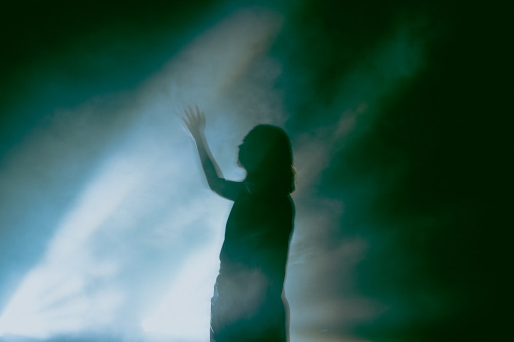 a woman standing in front of a light in the dark