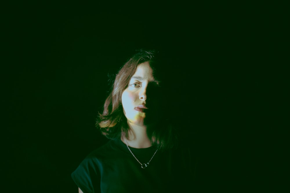 a woman standing in the dark with a necklace on