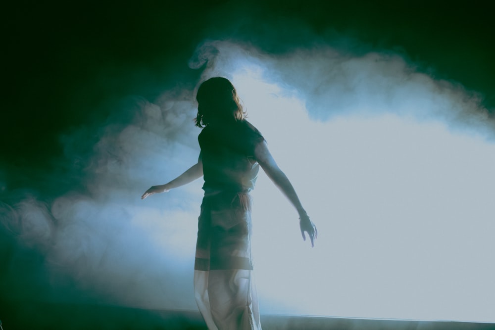 a woman standing on a stage in front of a cloud of smoke