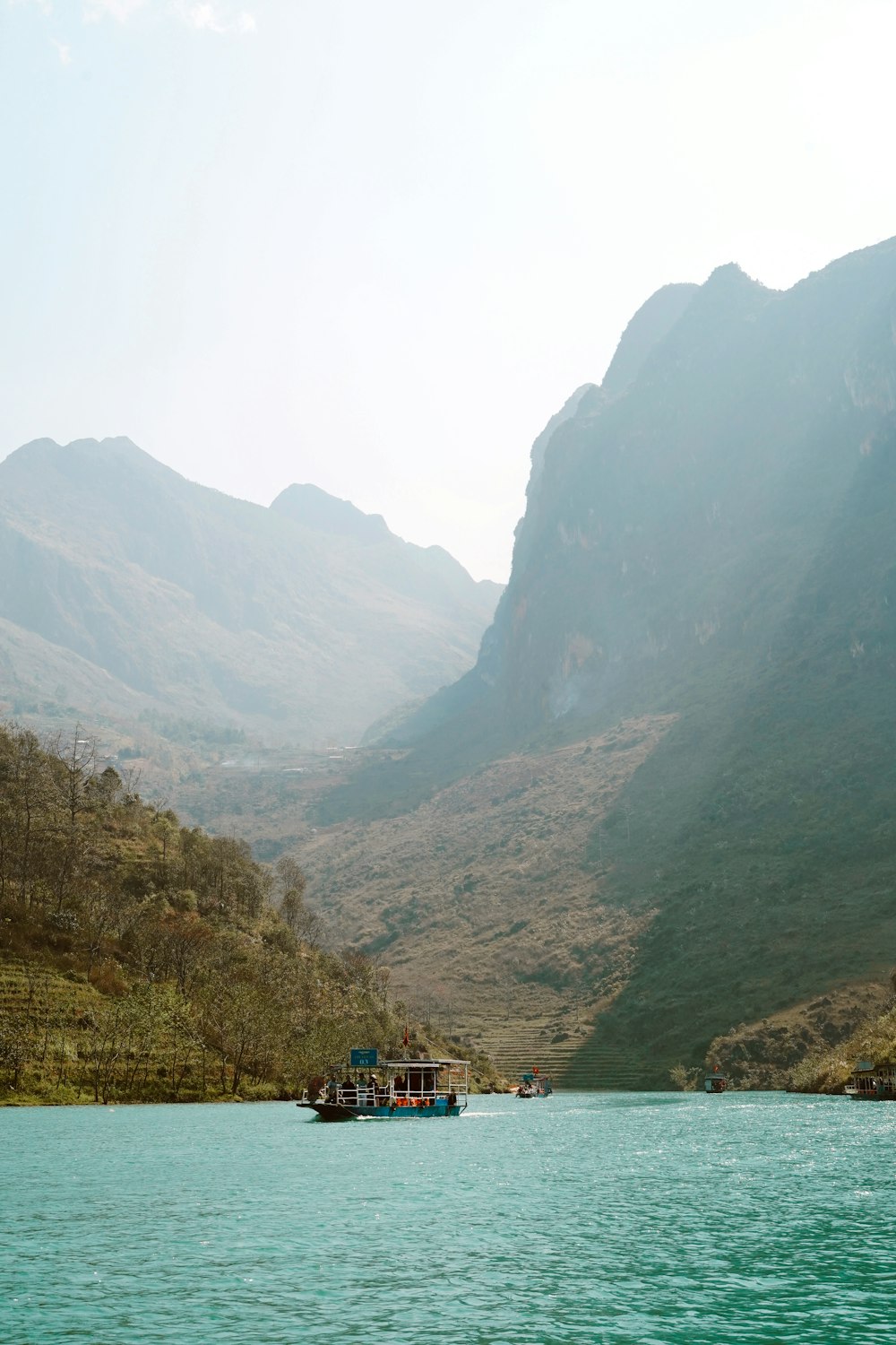 a boat traveling down a river next to a mountain range