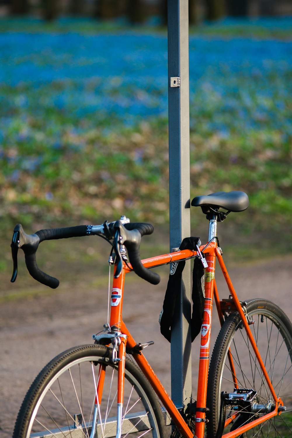 an orange bicycle is chained to a pole