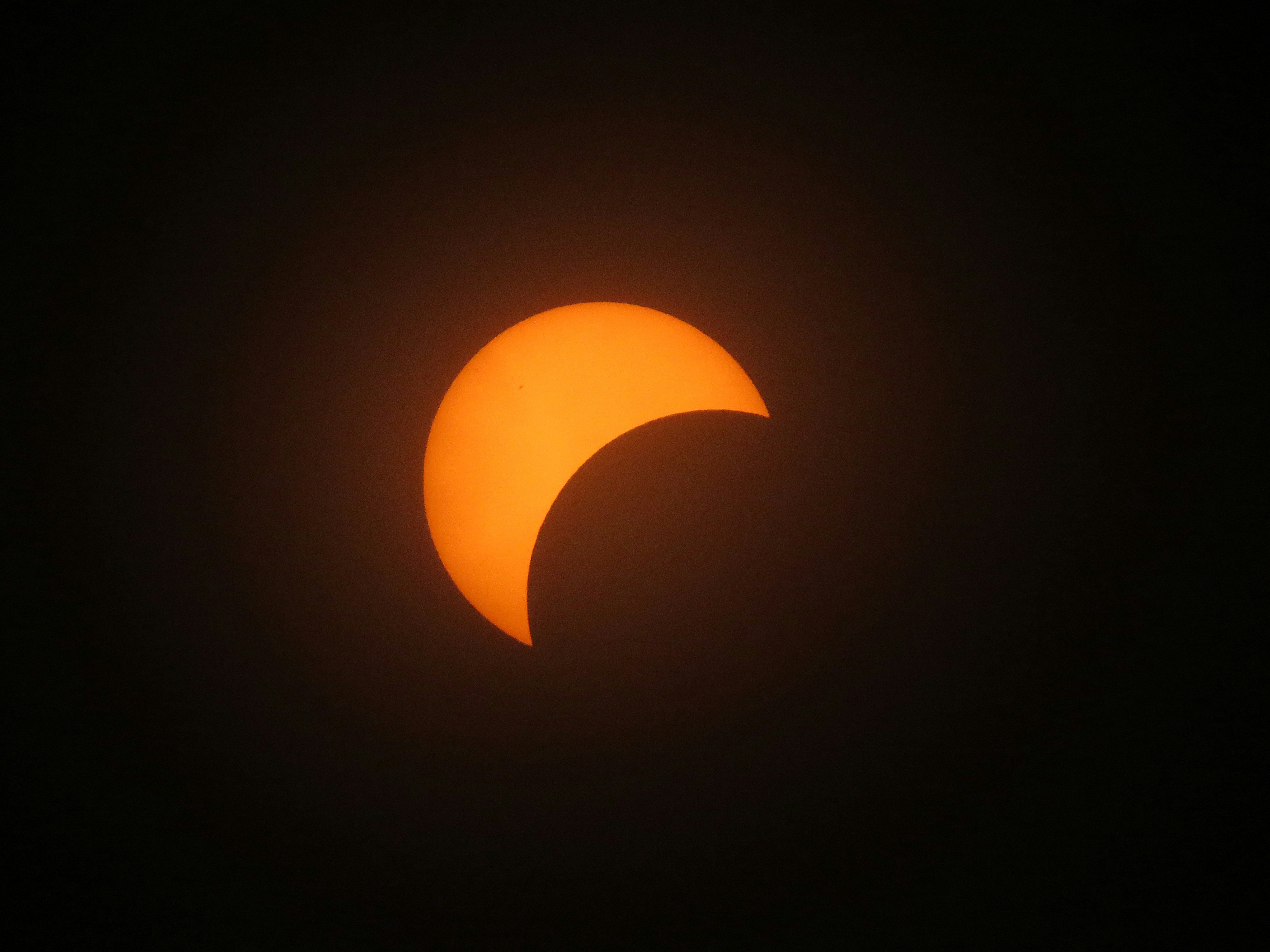 a partial solar eclipse seen through the clouds