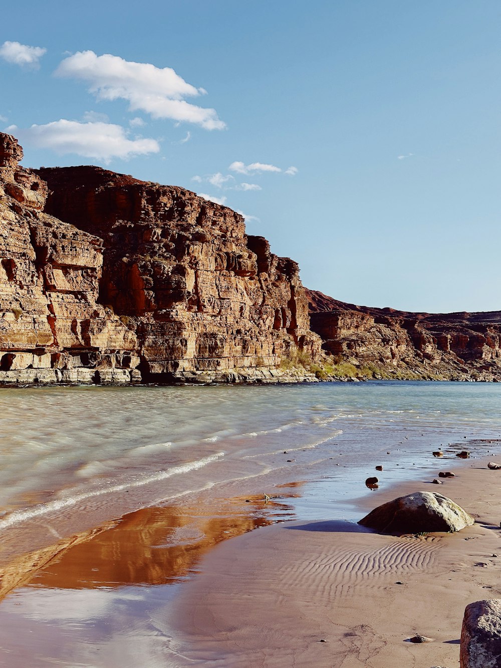 a sandy beach next to a rocky cliff