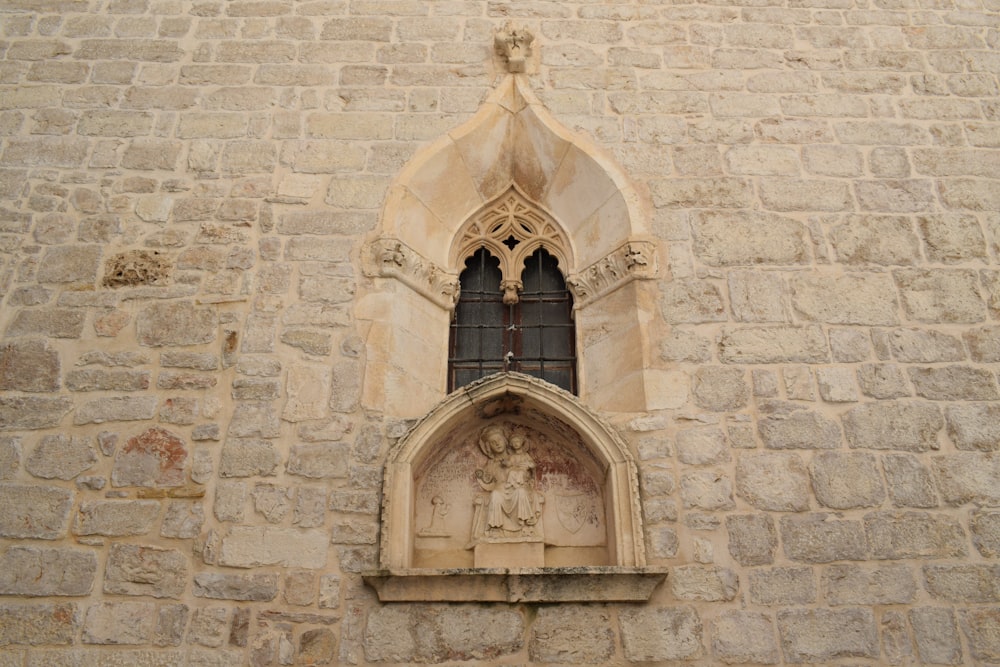 a stone building with a window and a statue